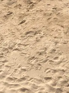 Gold colored sand with many footprints in it